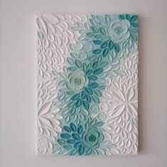 a white and blue wall hanging on the side of a wall with flowers in it