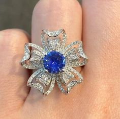 a woman's hand with a blue and white diamond ring on top of it