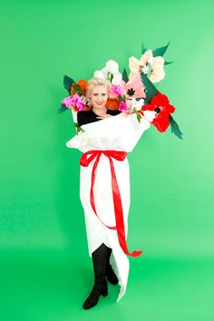 a woman is holding flowers in her arms and posing for the camera on a green background