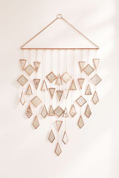 a white wall with a metal frame hanging from it's side and lots of different shapes