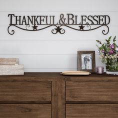 a wooden dresser topped with drawers and a metal sign that says, thank you and be loved