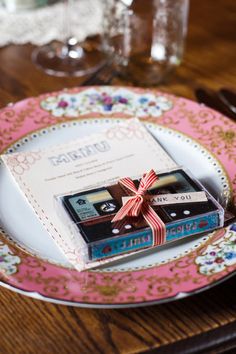 two chocolates wrapped in red ribbon sitting on top of a pink and white plate