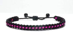 a black and pink bracelet with beads on it's end, sitting on a white surface