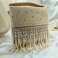 This beautiful piece is adorned with pearl beads and tassels giving it a look of pure elegance.  The bag comes with a shoulder strap allowing for it to be worn in different ways and can work with a variety of different looks! Chic Beige Shoulder Bag With Tassels, Chic Tassel Clutch Bag, Chic Clutch Bag With Tassels, Elegant Shoulder Bag With Pearl Handle, Chic Formal Bag With Fringe, Chic Formal Bags With Fringe, Chic Formal Fringe Bag, Chic Formal Fringe Bags, Chic Tassel Clutch Shoulder Bag