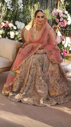 a woman sitting on top of a chair in a wedding dress with flowers behind her