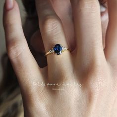 a woman's hand with a blue ring on top of her finger and an engagement band