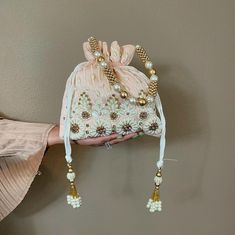 This Pearl and Zirconia and Sequin studded Peach Potli is a beautifully handcrafted Indian Batwa Bag, perfect for adding a touch of traditional elegance to any occasion. The bag features a stunning peach base adorned with intricate pearl embroidery, creating a luxurious and festive appeal. The shimmering sequins add a glamorous flair, making it an ideal accessory for brides or wedding guests. ✅ How To Order Please select your color in option. ✅ SPECIFICATIONS: ⦿  Available in 3 colors : Hot pink, Baby blue, Peach  ⦿ Dimension: Length 9", Width 9" ⦿ Item Type: Indian Potli Bag ⦿ Material: Fabric, Sequins, Zardosi, Etc. ⦿ Gender: Women ✅ FEATURES: ⦿ Made using beads and sequins and rhinestones on silk fabric ⦿ Ethnic and contemporary ⦿ Has a drawstring closure ⦿ Add a touch of glamour ⦿ Plea Return Gifts Indian, Bride Clutch, Purse For Wedding, Potli Bag, Pearl Embroidery, Indian Gifts, Return Gift, Potli Bags, Blue Peach