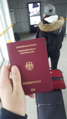 a person holding up a red passport at an airport