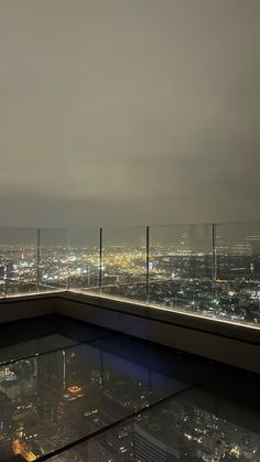 a view from the top of a building at night with city lights in the distance