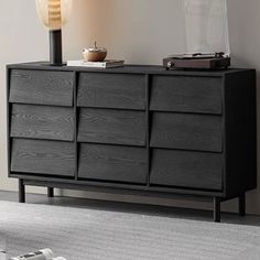 a black dresser with drawers and a lamp on top