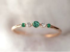 three stone diamond and emerald ring on white background