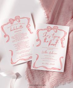 two pink and white wedding stationery cards on top of a pink blanket with ribbon