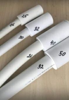 four white plastic tubes sitting on top of a wooden table with numbers printed on them