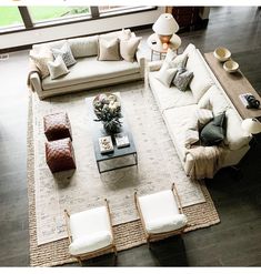 a living room with couches, chairs and tables in front of a large window