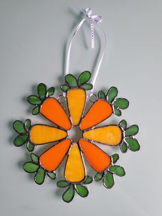 an orange and green flower ornament hanging from a string