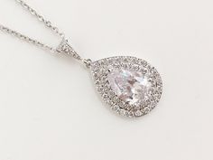 Beautiful! clear cubic zirconia bridal tear drop pendant and necklace in rhodium plated brass setting. Necklace pendant features a large teardrop with pear cut cubic zirconia center surrounded by two rows of tiny zirconia crystals which dangles from a cubic zirconia detailed bail. Length of the rhodium plated chain is 18 inches and comes with 2 inches extender and lobster clasp. For matching earrings click: https://www.etsy.com/listing/495791548/teardrop-crystal-earrings-bridal-cubic?ref=listing White Gold Drop Necklace With Diamond Accents For Wedding, Brilliant Cut Diamond White Drop Necklace For Wedding, White Gold Cubic Zirconia Drop Necklace For Wedding, Silver Bridal Necklace With Brilliant Cut Pear-shaped, White Gold Diamond Cut Drop Necklace For Wedding, Formal Cubic Zirconia Teardrop Pendant Bridal Necklace, Formal Cubic Zirconia Teardrop Bridal Necklace, Diamond White Cubic Zirconia Drop Necklace With Teardrop Pendant, Teardrop Brilliant Cut Necklace For Wedding