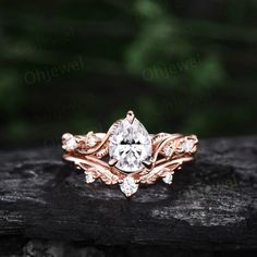 a rose gold engagement ring set with a pear shaped center stone surrounded by leafy vines