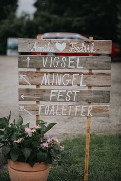 a wooden sign sitting in the grass next to a potted plant