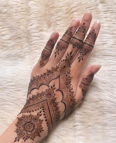 a woman's hand with henna tattoos on it