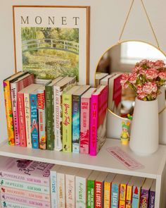 there is a book shelf with many books on it and a vase full of flowers