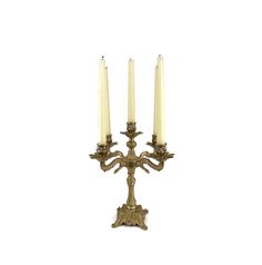 three candles are lit in an ornate brass candelabra on a white background