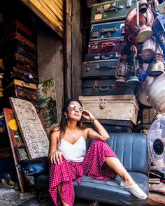 a woman sitting on top of a chair in front of a pile of luggage