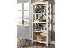 a white bookcase sitting on top of a wooden floor next to a door and rug