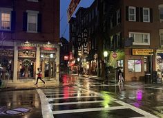 people crossing the street at night on a rainy day