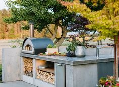 an outdoor bbq grill with various food items on it and trees in the background