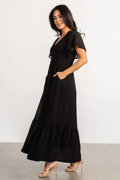 Get ready to turn heads in The Monica Smocked Dress—your new go-to for easy, feminine style. In classic black with flutter sleeves, this dress is all about charm. And the hidden pockets keep your essentials close while you steal the show. Evening V-neck Maxi Dress With Smocked Back, Solid V-neck Midi Dress With Smocked Back, Chic Maxi Dress With Smocked Bodice And Empire Waist, Chiffon Maxi Dress With Ruched V-neck, Ruched Chiffon Maxi Dress With V-neck, Chic V-neck Smocked Beach Dress, Chic V-neck Smocked Dress With Ruffles, Flowy V-neck Maxi Dress For Cocktail, Elegant V-neck Midi Dress With Elastic Waistband