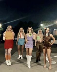 four women dressed in costumes standing on the street at night