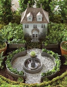 a miniature house is surrounded by potted plants and small water features in the garden