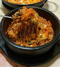 two black pans filled with food on top of a table