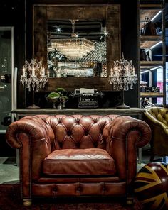 a brown leather chair sitting in front of a bar with chandelier hanging from the ceiling