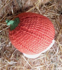 an orange knitted hat sitting on top of hay