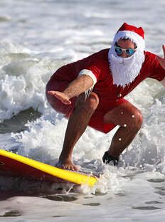 a man dressed as santa claus surfing in the ocean