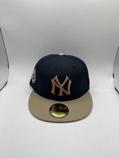 the new york yankees'gold and navy fitted - back hat is displayed in front of two other hats