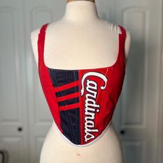 Over-bust corset with flexible boning and silk ribbon closure.  Made from a Cardinals jersey with white cotton pinstripe in back. Fits a small  - US 2-6 (sizing is pretty flexible due to the lace up closure) Mannequin's measurements - Waist: 27" Bust: 37" Let me know if you have any questions. Stretch Corset With Tank Straps And Corset Back, Stretch Corset With Corset Back And Tank Straps, Red Fitted Top With Boned Bodice, Fitted Corset With Tank Straps, Fitted Underbust Top With Corset Back, Sleeveless Lace-up Back Corset, Fitted Cotton Top With Corset Back, Fitted Overbust Top With Corset Back, Fitted Overbust Tops With Straps