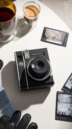 an old camera sitting on top of a table next to some cards and cups with drinks