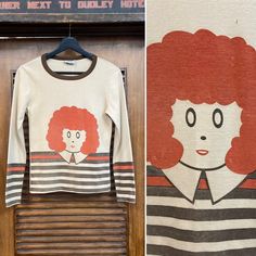 "Vintage 1960's \"Orphan Annie\" Glam Mod Pop Art Knit Long Sleeve T-Shirt. No Size Tag. Please check the measurements below. Good vintage condition. Fading and some very damage. (see photos) The label is \"Varsity\". Original 1960's. Long sleeve fitted T shirt with pop art Orphan Annie. All Sales Final. Please ask any questions before purchase. Take a look at our Store for more Vintage Clothing - VintageOnHollywood. MEASUREMENTS Shoulder to Shoulder: 14 1/2\" Underarm to Underarm: 16\" Outer Sl Vintage Screen Print Tops For Fall, Vintage Screen Printed Tops For Fall, Retro Long Sleeve Tops With Screen Print, Retro Graphic Print Tops For Fall, Retro Cotton Tops With Vintage Print, White Vintage Tops With Retro Print, 1970s Long Sleeve Tops With Retro Print, 1970s Style Long Sleeve Tops With Retro Print, 1970s Retro Print Long Sleeve Tops