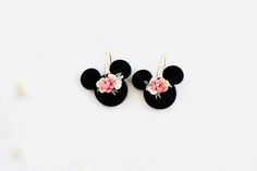 the mickey mouse earring is decorated with pink and white flowers on black velvet ears