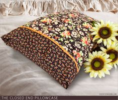 two sunflowers sitting on top of a bed next to a black and white pillow