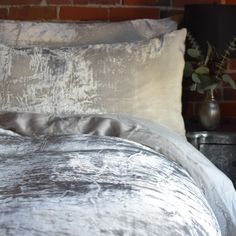 a close up of a bed with a brick wall in the background and a plant next to it