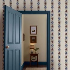 an open door leading to a hallway with wallpaper on the walls and a table next to it