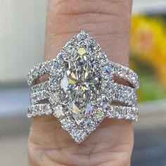 a close up of a person's hand holding a ring with a large diamond