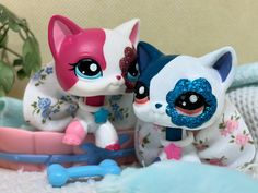 two little kittens sitting next to each other on a white blanket with pink and blue flowers