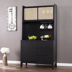 a black cabinet with baskets and bowls on it next to a vase filled with flowers