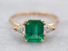 Pretty and luxurious, this emerald and diamond ring has a timeless design. The emerald is a vibrant Kelly green with excellent clarity. The trillion-cut diamonds don't overwhelm the center stone and instead enhance it with just the right amount of sparkle. Highly versatile, this ring is a true classic!Metal: 14K Yellow GoldGem: Emerald 1.41 CaratsGem Measurements: 7.3 x 6.2 mm, Emerald CutAccents: 2 Diamonds totaling .33 Carats, SI in Clarity, H in ColorRing Size: 6.75Marks: “14K*” Stamped on the inside band Emerald Anniversary, Engagement Ring Three Stone, Colombian Emerald Ring, Emerald Ring Vintage, Garnet And Diamond Ring, Sapphire Solitaire Ring, Ring Three Stone, Emerald And Diamond Ring, Pink Tourmaline Ring