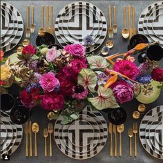 a table topped with plates and flowers on top of each other next to gold utensils