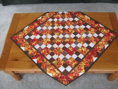 a coffee table with a quilted top and wooden legs on the floor in front of a couch